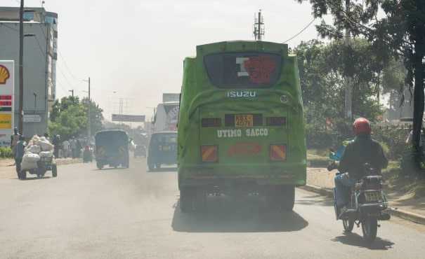 A bus drives along a road spewing a large amount of exhaust fumes in to the air, Nairobi, Kenya